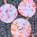 Three finished jack-o-lantern craft for Halloween pumpkins decorated like mummies with white tissue paper strips and googly eyes.