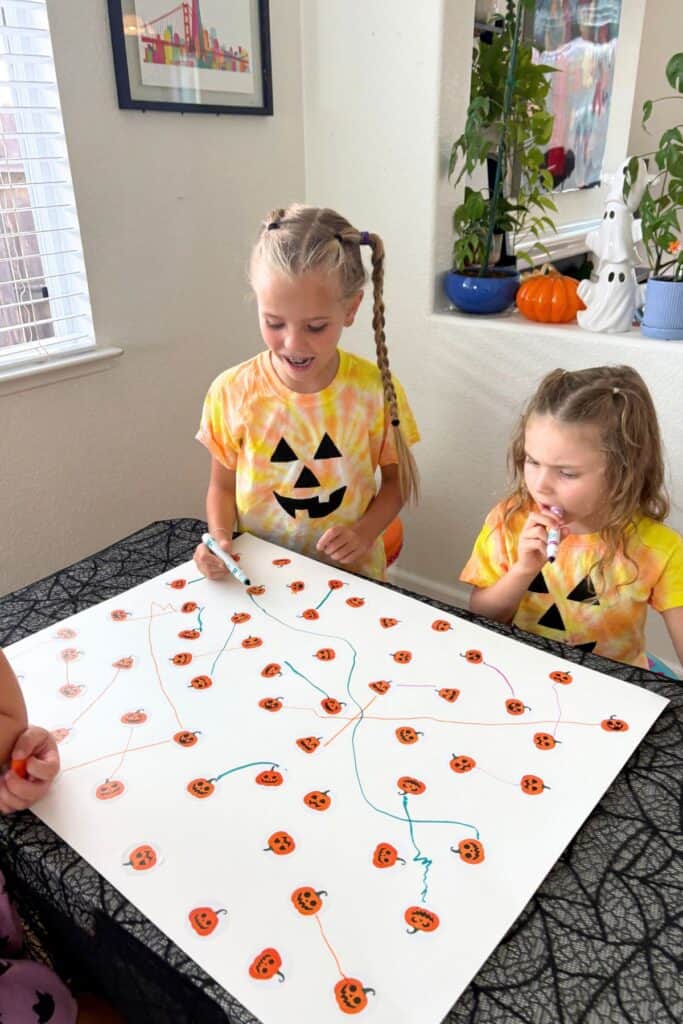 Kids working together on a preschool Halloween activity matching pumpkin stickers with colorful markers.